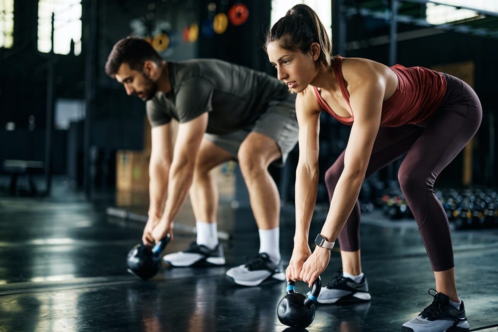 Para ćwicząca z kettlebell na siłowni — trening siłowy